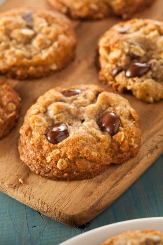Oatmeal chocolate chip cookies on a wooden cutting board.