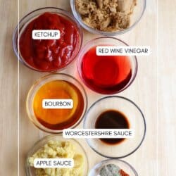 Ingredients for apple bourbon BBQ sauce in clear glass bowls on a wooden table.