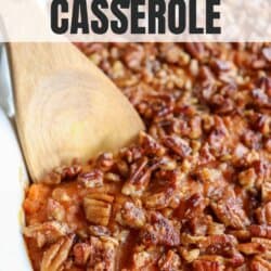 Sweet potato casserole topped with a caramel pecan streusel in a white casserole dish with a wooden spoon scooping out some of the mixture.