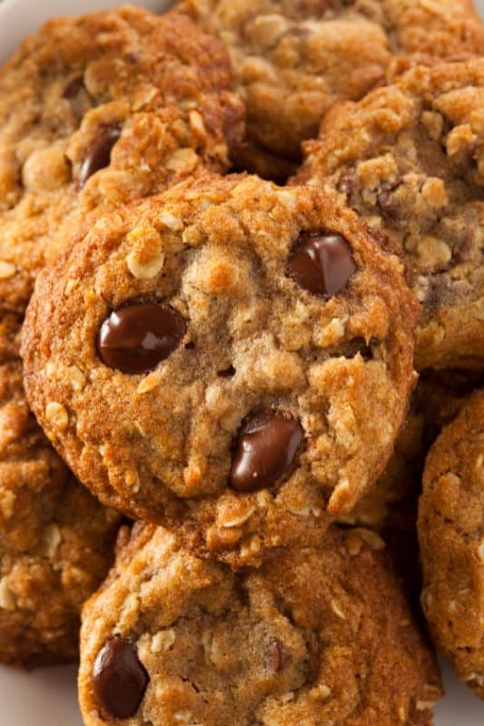 Oatmeal chocolate chip cookies stacked on a white plate.