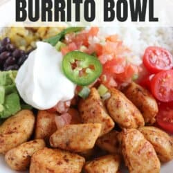 Cooked chicken bites with seasoning in a large white bowl with rice, diced avocado, black beans, corn kernels, cherry tomatoes, pico and sour cream topped with a slice of jalapeno and lime.