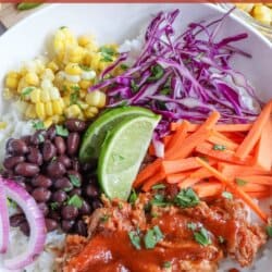 Pulled pork and vegetables over rice in a large white bowl topped with barbecue sauce.