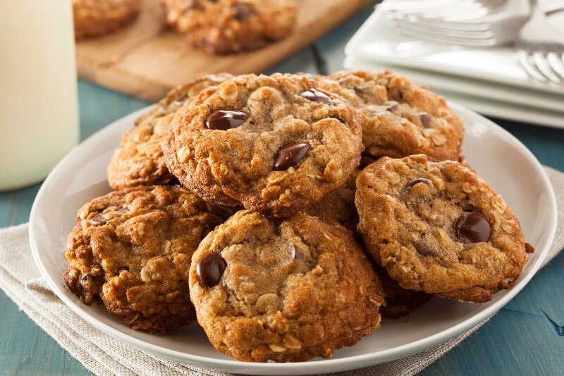 Oatmeal chocolate chip cookies stacked on a white plate.