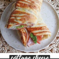 Flatbread wrap filled with lettuce, tomato, ham and cheese, cut in half diagonally and placed on a cream plate.
