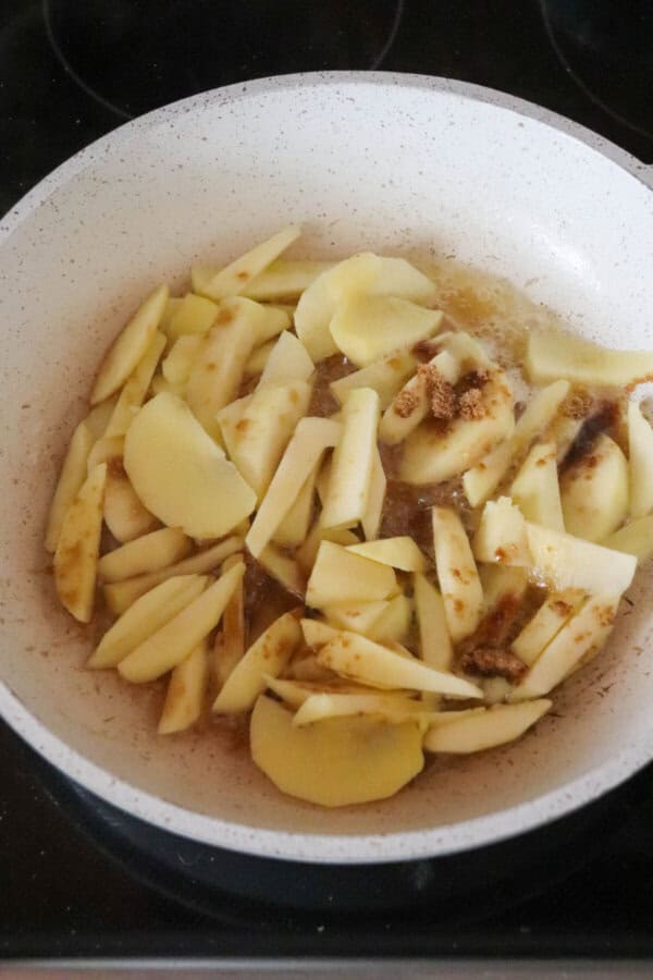 Sliced apples in a white skillet.