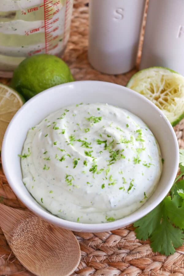 White bowl of Mexican crema sauce topped with lime zest.