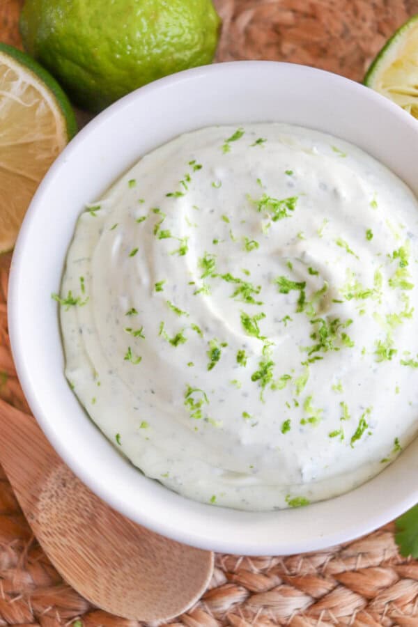 White bowl of Mexican crema sauce topped with lime zest.
