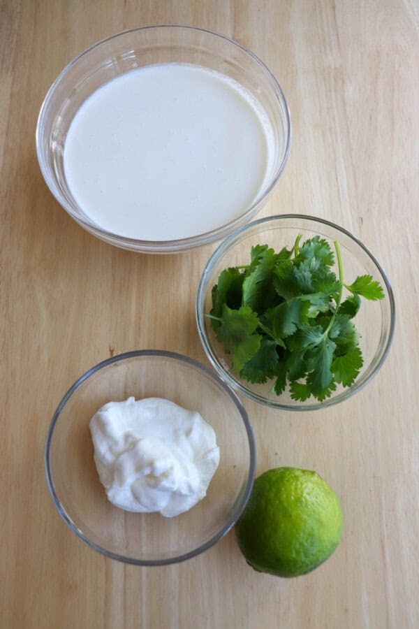 Crema ingredients in clear glass bowls on a wooden table.