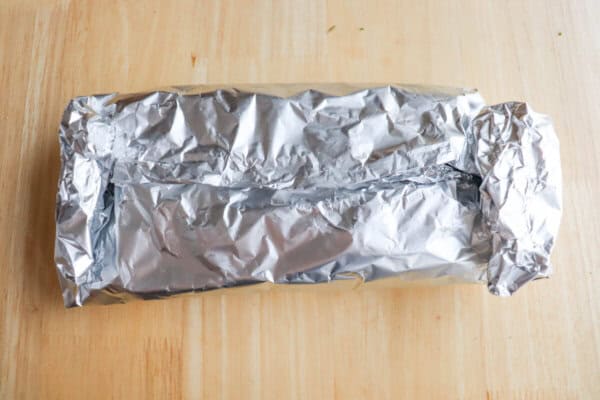 Foil packet of asparagus on a wooden table.