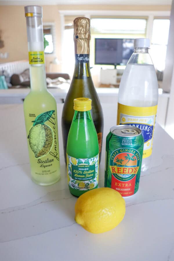 Ingredients for limoncello spritz on a white counter.