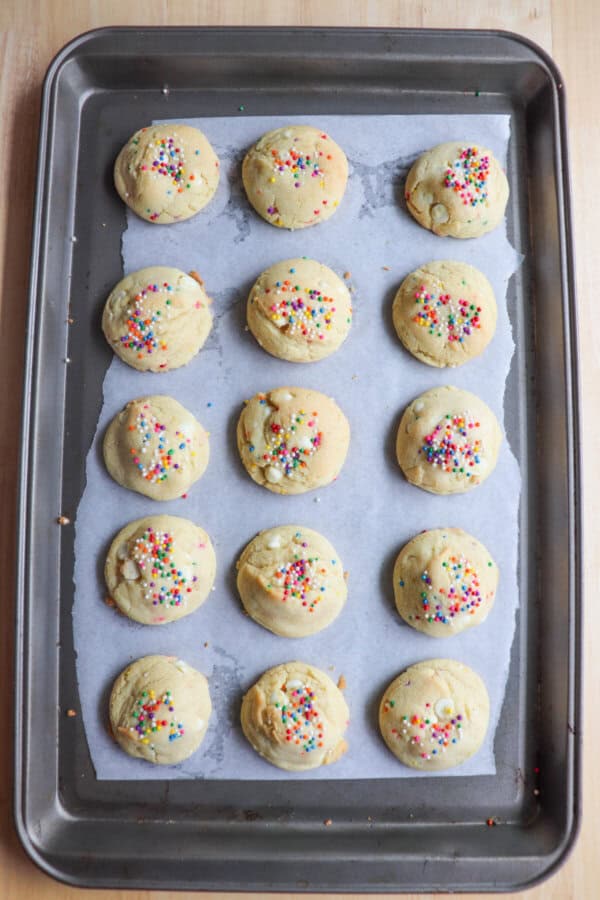 Rainbow sprinkle pudding cookies baked on a parchment paper lined baking sheet.
