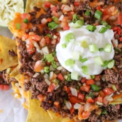 Nachos piled high with taco meat, picco, salsa and green onions.