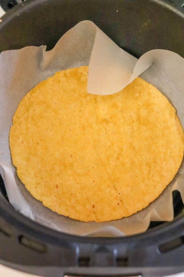 Corn tortilla in a parchment paper lined air fryer basket.