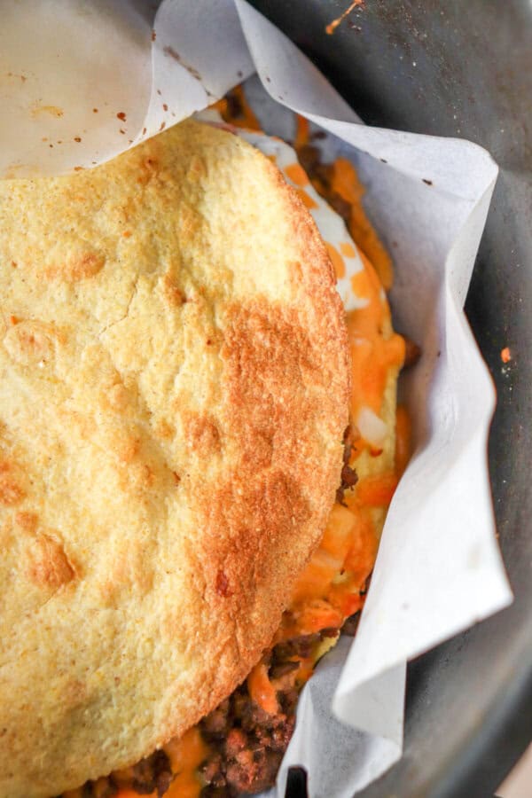 Baked corn tortilla in the basket of an air fryer.