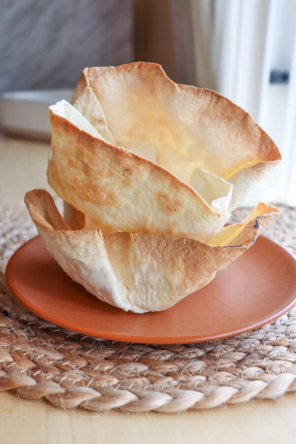 Stack of taco bowls on an orange plate.