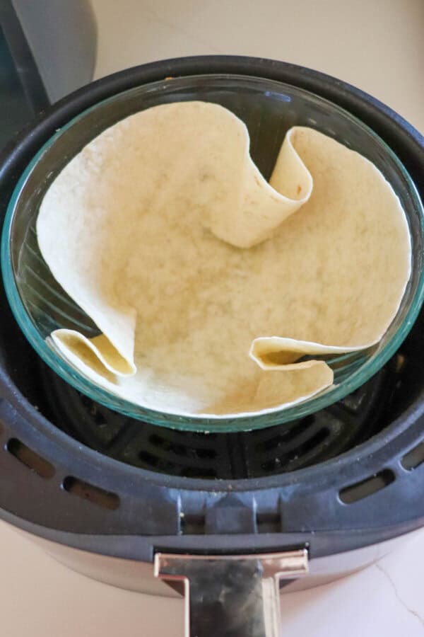 Large flour tortilla in the  basket of an airfryer.