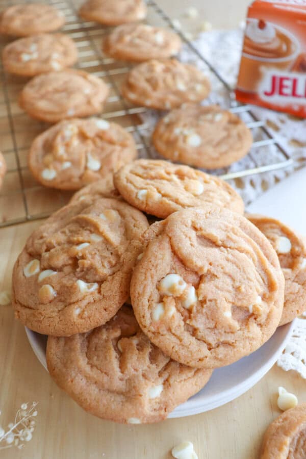 Butterscotch pudding cookies with white chocolate chips stacked on a white plate.