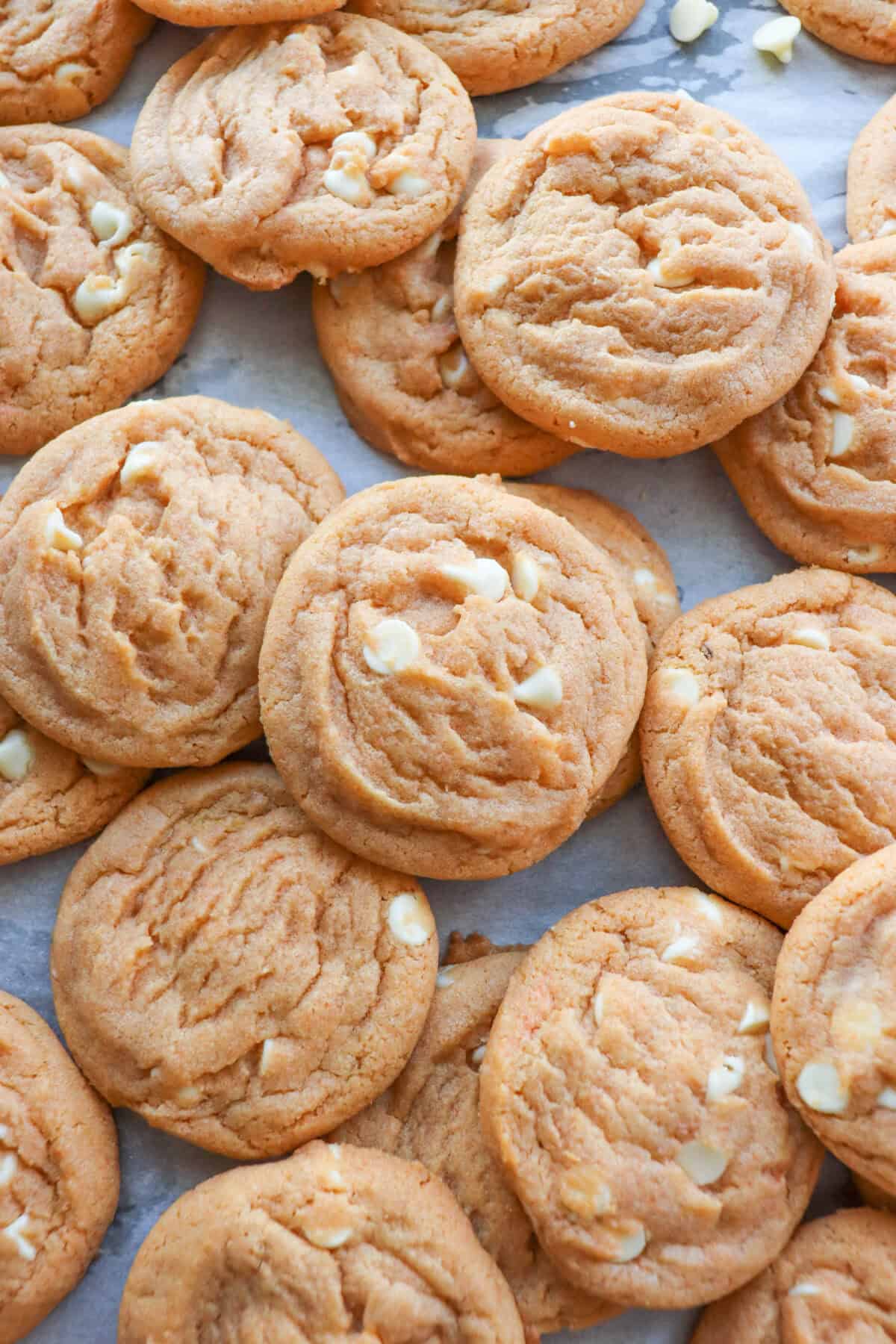 Butterscotch pudding cookies layered on a parchment paper lined cookie sheet.