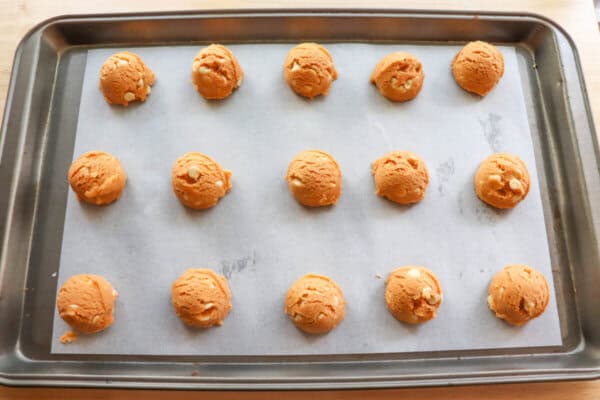 Butterscotch cookie dough balls on a parchment lined baking sheet.