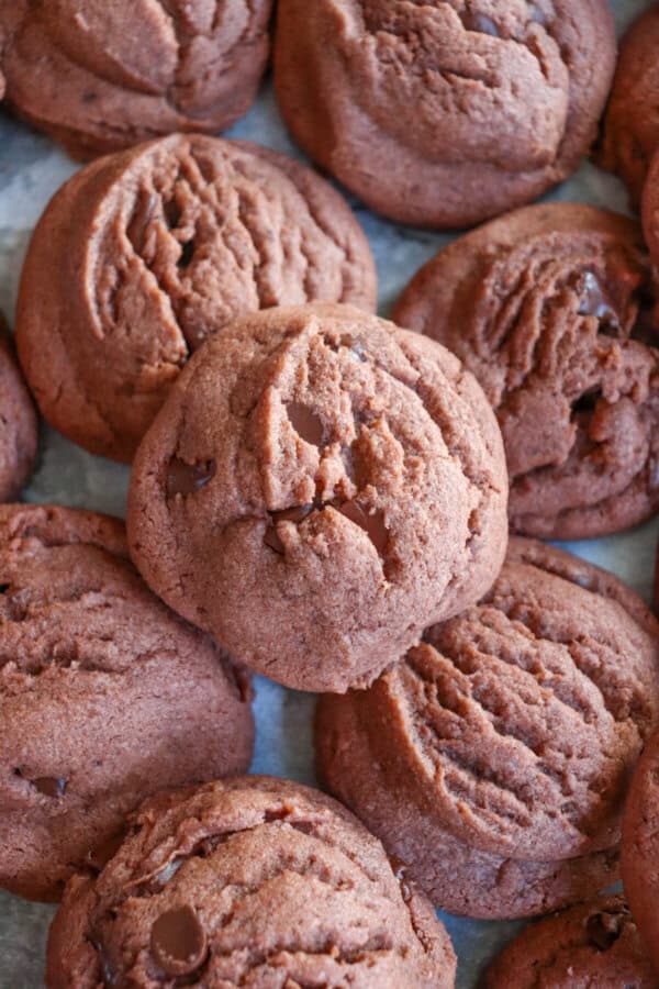 Chocolate pudding cookies piled on a parchment paper lined baking sheet.