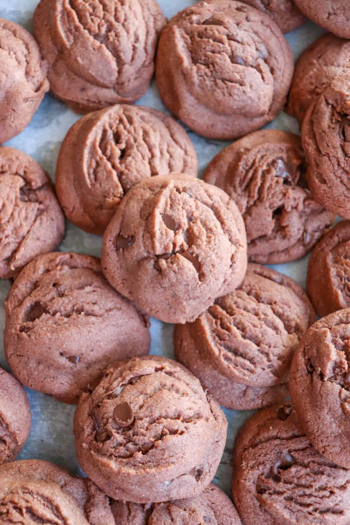 Chocolate pudding cookies piled on a parchment paper lined baking sheet.