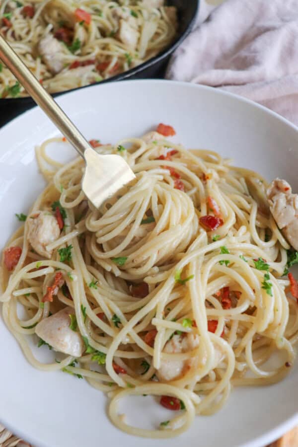 Chicken pasta with bacon bits and spaghetti in a white bowl.