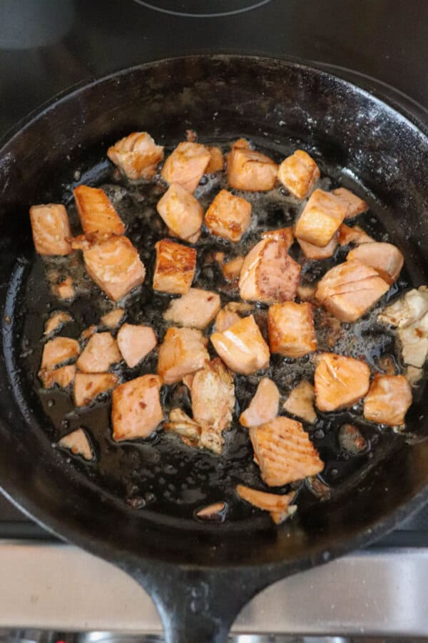 Salmon bites cooked in a cast iron skillet.