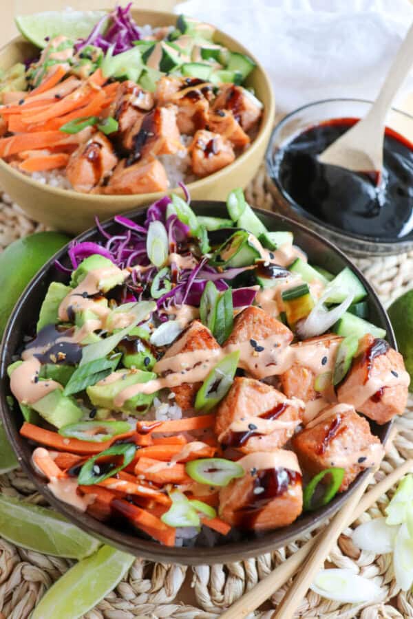 Grilled salmon and vegetables on a bowl of rice drizzled in teriyaki sauce and spicy mayo.