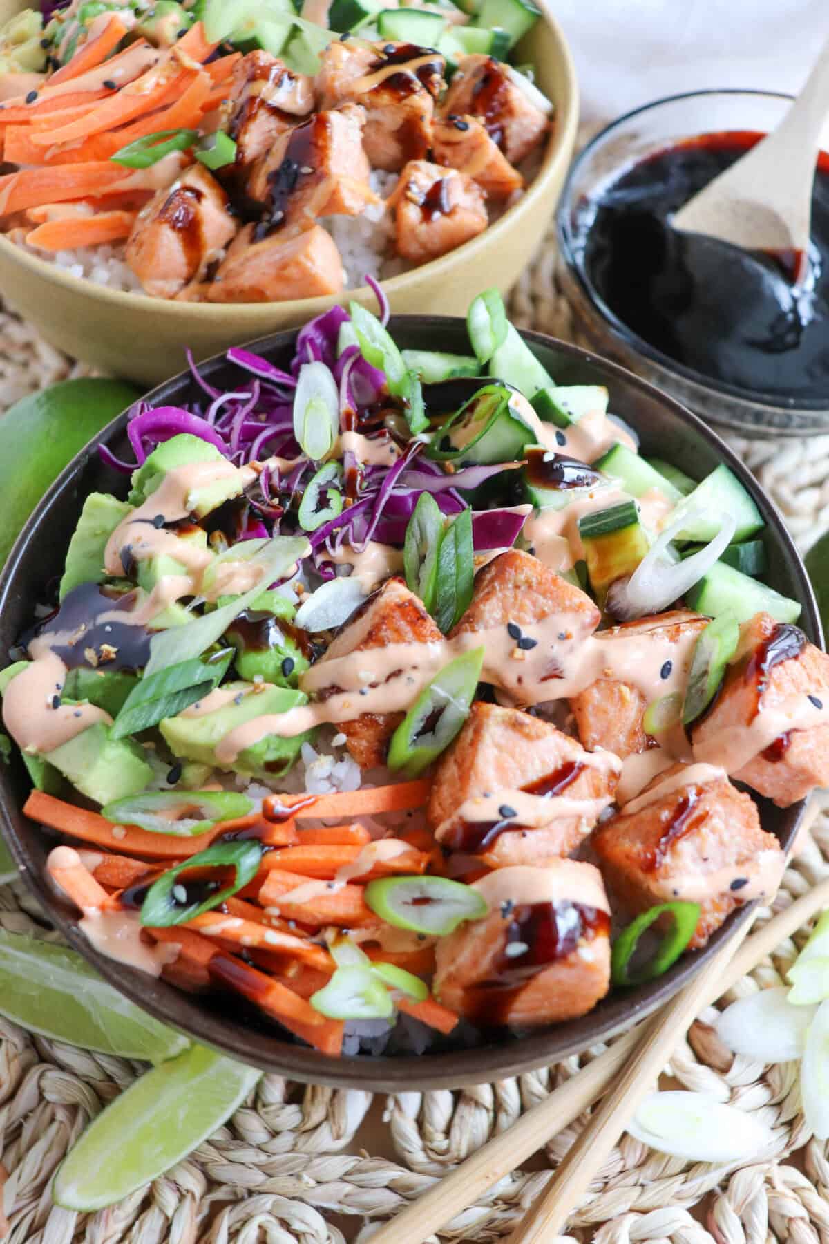 Grilled salmon and vegetables on a bowl of rice drizzled in teriyaki sauce and spicy mayo.