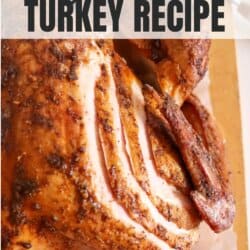 Whole turkey with sliced cut into the breast on a wooden cutting board.