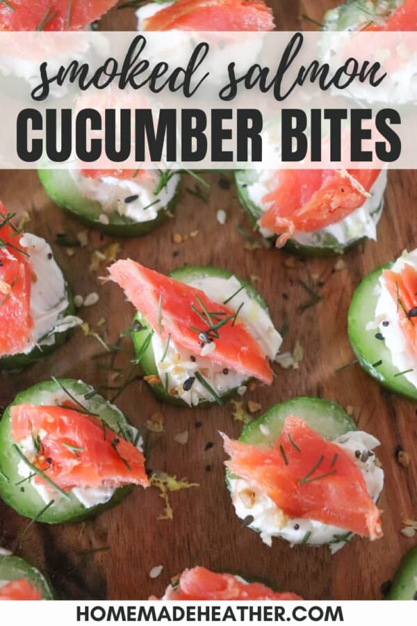 Small rounds of cucumber slices topped with cream cheese, smoked salmon and garnished with fresh dill and lemon zest on a wooden cutting board.