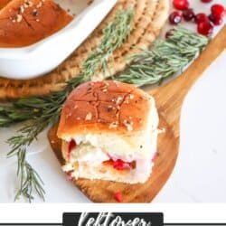 Hawaiian rolls filled with turkey and cranberry sauce in a white baking dish.
