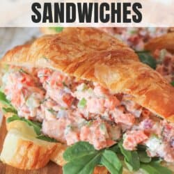 Smoked salmon salad in a fresh croissant with arugula on a wooden cutting board.