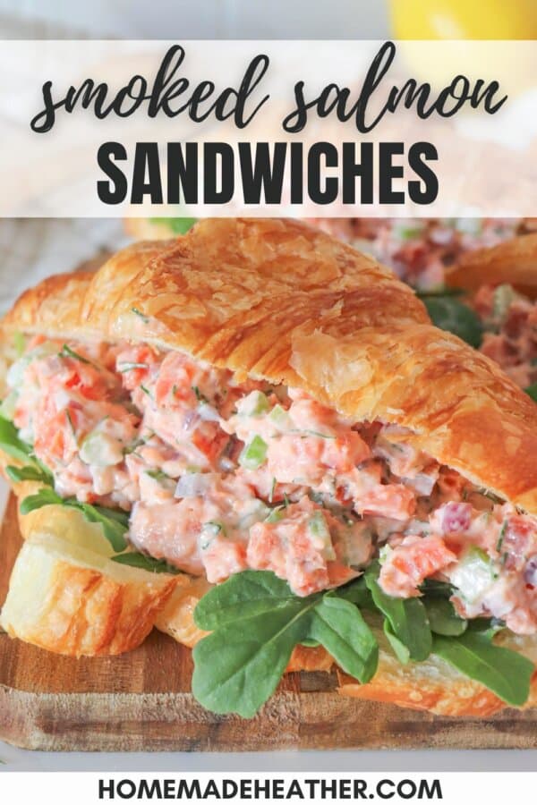 Smoked salmon salad in a fresh croissant with arugula on a wooden cutting board.
