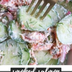 Sliced cucumbers with pieces of smoked salmon and pickled onions covered in a creamy dill sauce in a white bowl.