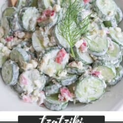 Sliced cucumbers in tzatziki sauce with diced pickled onions and dill in a white bowl.