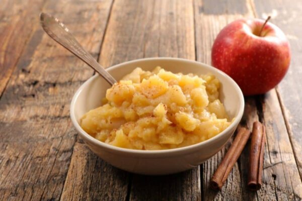 Apple sauce in a white bowl on a wooden table.