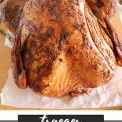 Whole turkey with sliced cut into the breast on a wooden cutting board.
