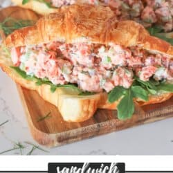 Smoked salmon salad in a fresh croissant with arugula on a wooden cutting board.