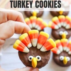 Round nutter butter chocolate covered cookie with candy corn feathers, candy eyes and an m&m beak.