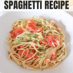 Cooked spaghetti noodles topped with pieces of smoked salmon and garnished with fresh dill in a white bowl.