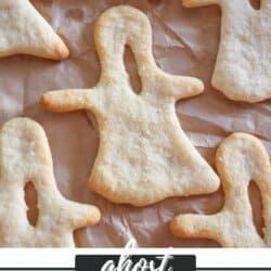 Breadsticks in the shape of ghosts on parchment paper.
