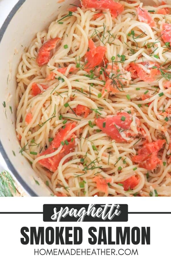 Cooked spaghetti noodles topped with pieces of smoked salmon and garnished with fresh dill in a white dutch oven.