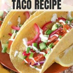 Corn tortillas on an orange plate filled with smoked salmon and diced vegetables drizzled in crema.
