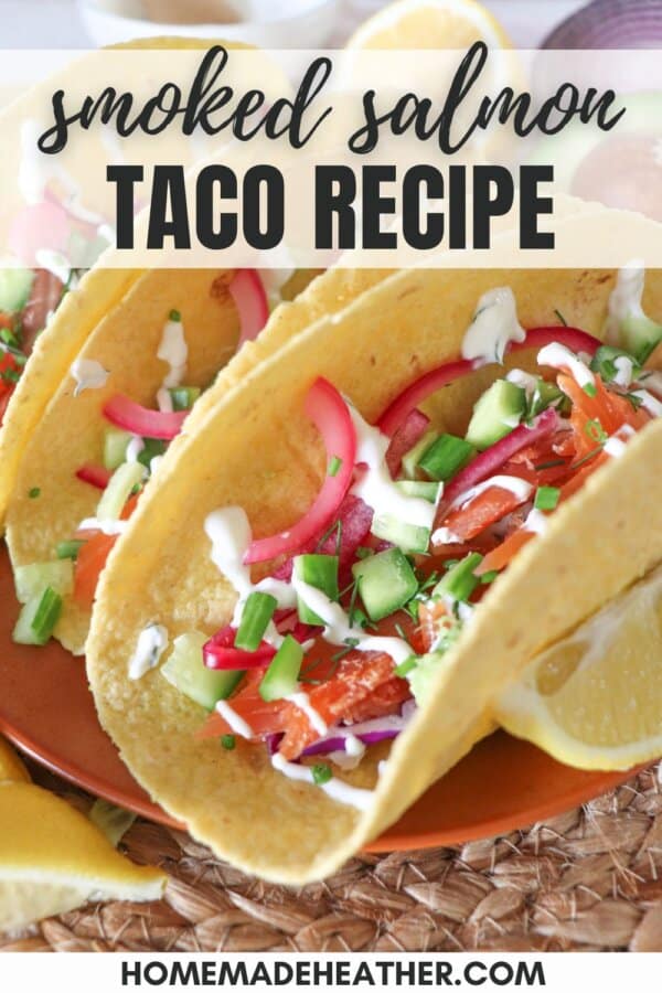Corn tortillas on an orange plate filled with smoked salmon and diced vegetables drizzled in crema.