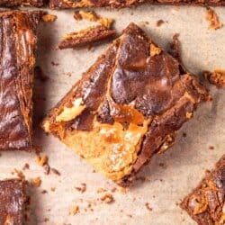 Chocolatey brownies with peanut butter swirls, cut into squares on parchment paper.