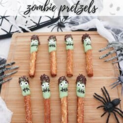 Pretzel sticks half dipped in green chocolate and dipped in brown sprinkles to create hair and placed on a wooden cutting board.