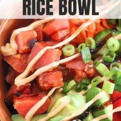 An orange bowl filled with smoked salmon, shredded carrots, cucumber slices, cherry tomatoes, avocado, green onions, and drizzled with sauces, creating a visually appetizing and healthy dish.