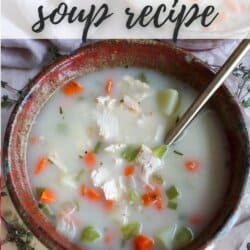 Cubes of celery, carrot and turkey in broth in a brown bowl with a spoon sticking out.