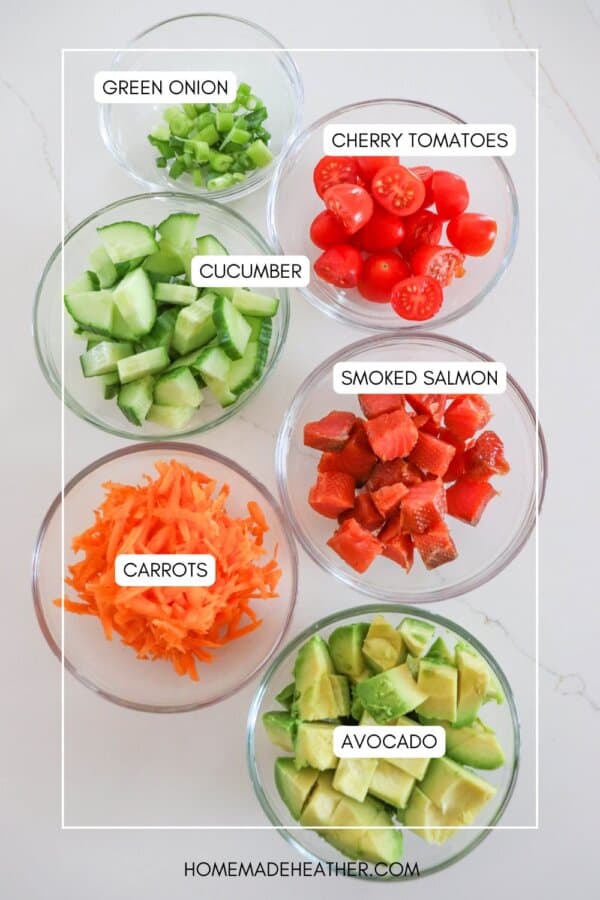 Ingredients for smoked salmon rice bowls in clear glass prep bowls on a white counter.